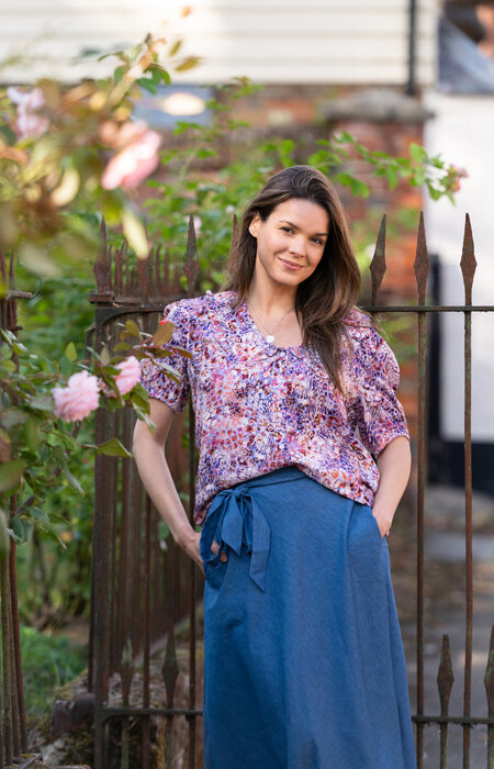 Model leaning on fence in floral blouse