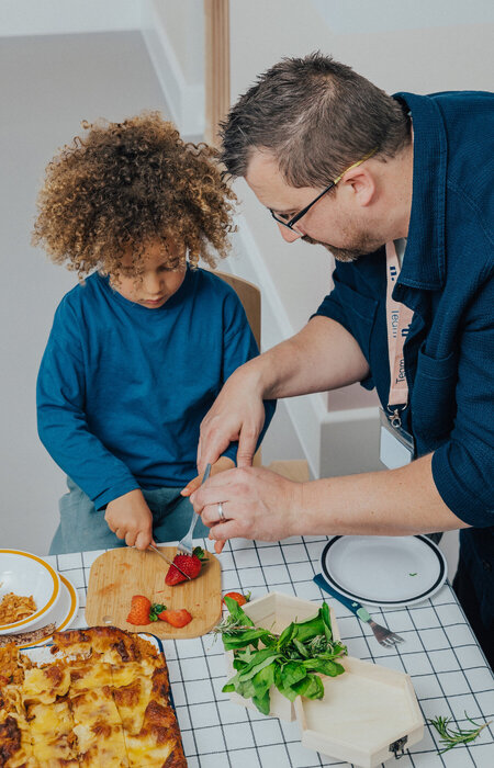 Child at table chopping strawberries