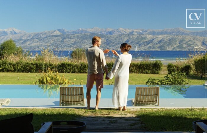 Couple raising a glass in front of pool on holiday