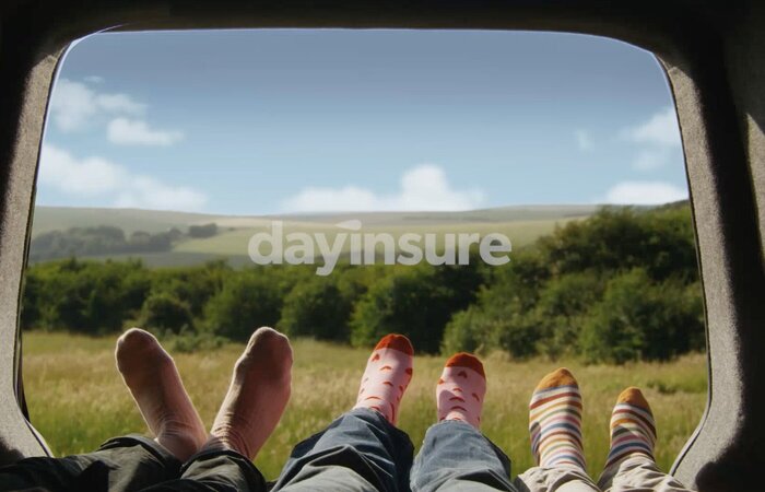 Three pairs of feet in socks in van with view