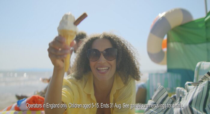 Woman on beach with ice cream and flake smiling