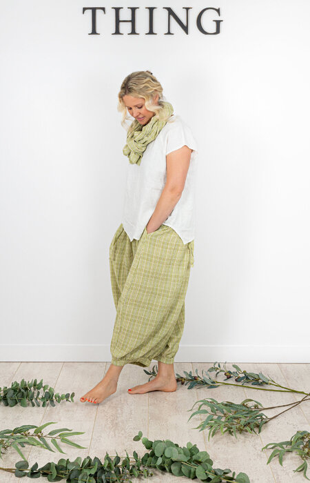 Model in green trousers and matching scarf looking down in studio