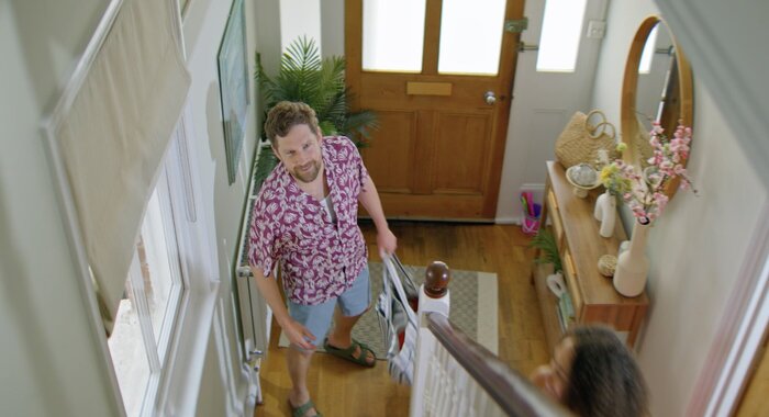 Man in colourful shirt in hallway looking up the stairs