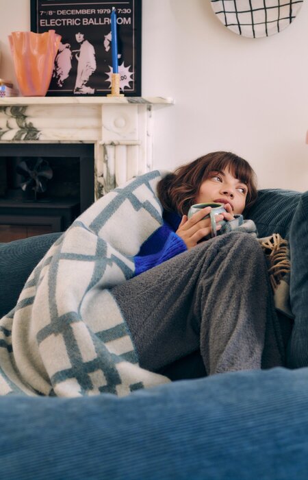 woman curled up on armchair under throw