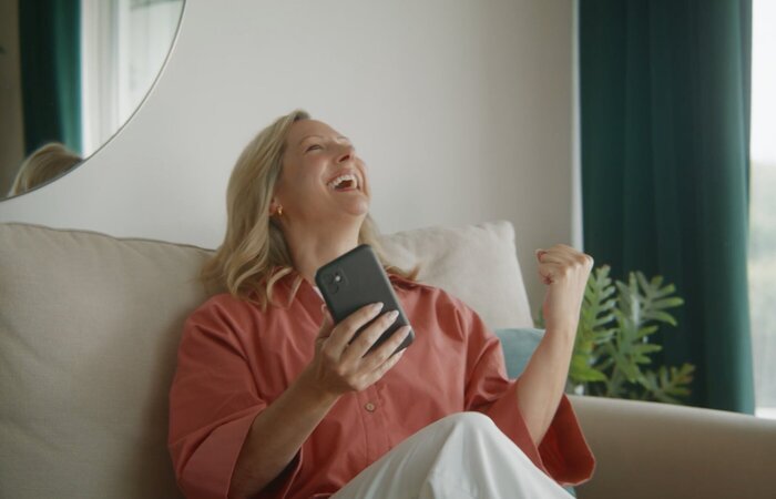 Female actor celebrating a purchase sat on sofa
