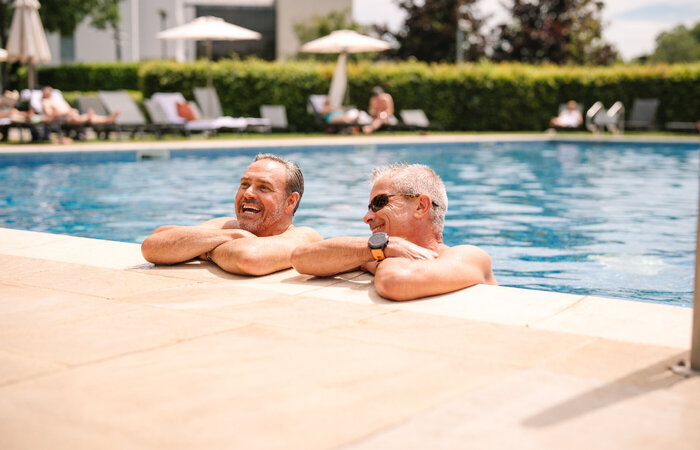 Two classic models laughing together at the side of the pool