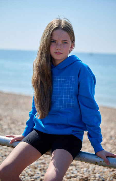 Female junior model sat on fence by sea