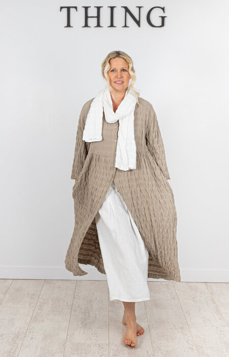 Model wearing beige flowing dress and scarf in studio