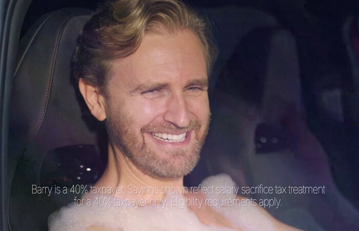 Male actor smiling in the car with no top on covered in bubbles