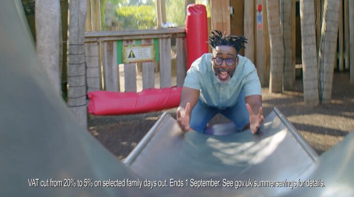 Man arms stretched out bottom of slide waiting to catch child