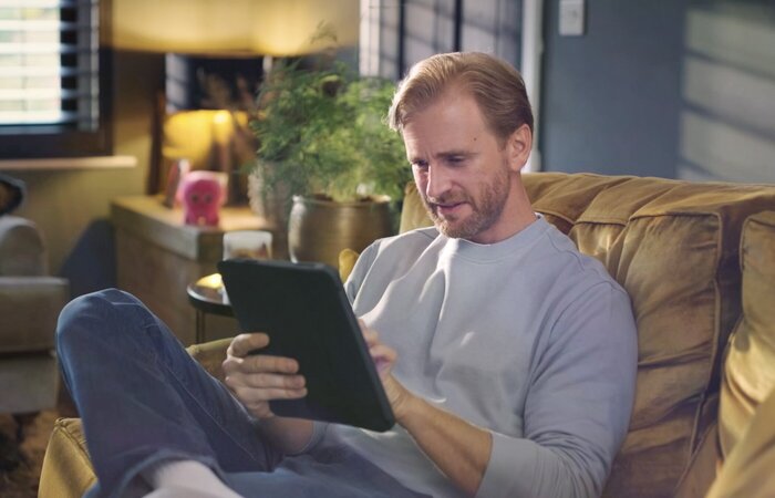 Actor sat on couch using tablet