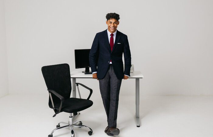 Male model smiling in office wear by desk