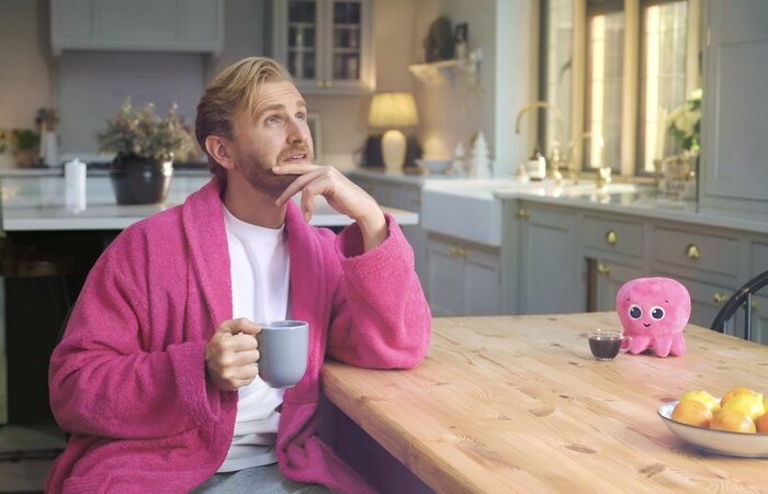 Actor in dressing gown with cup of tea in kitchen