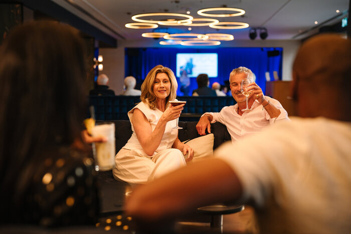 Classic model couple with drinks sat in lounge