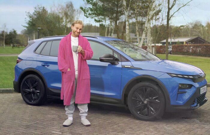 Actor in dressing gown in front of car with cup of tea