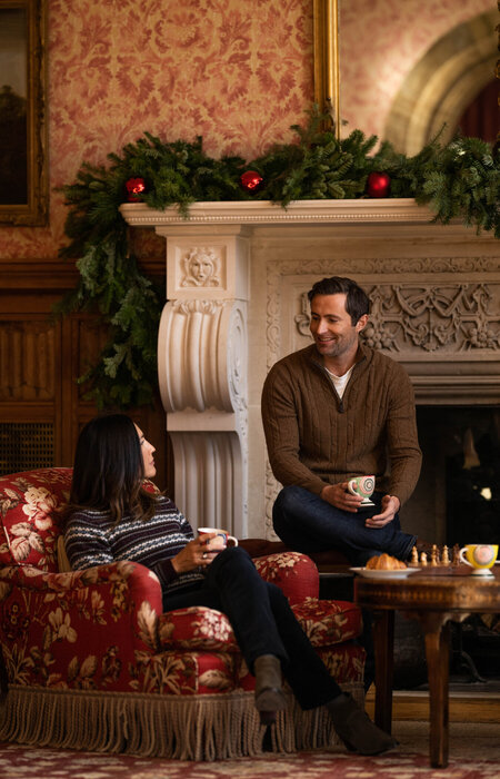 Model couple sitting together in front of fireplace