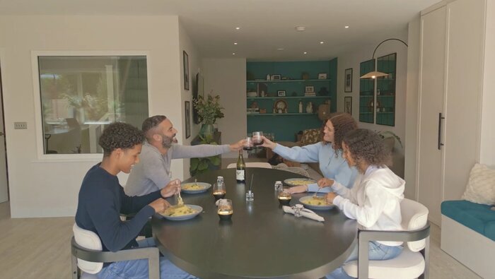 Model family at dining table raising a glass