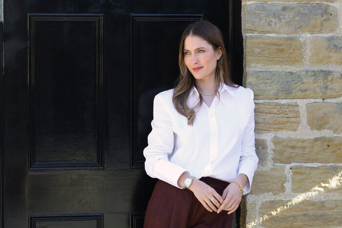 Female model in white shirt leaning against wall
