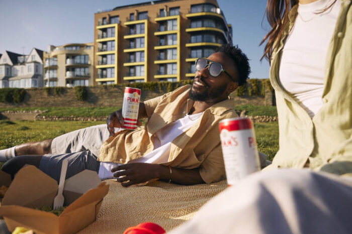 male model drinking lying on grass