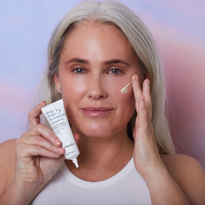 Woman holding beauty product applying cream