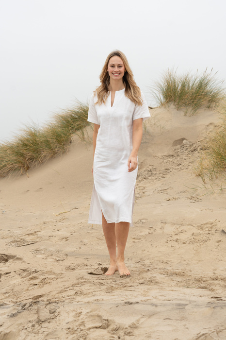 Model in white dress walking on beach smiling