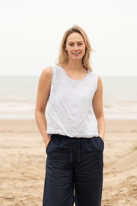 Model smiling on beach hands in pockets