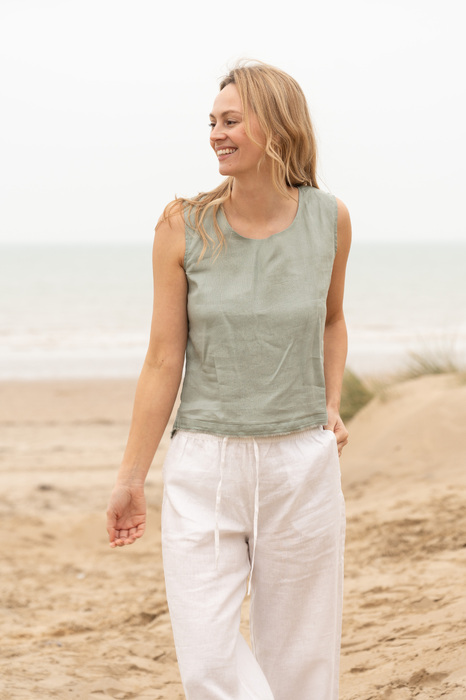 model in linen top and trousers on beach laughing