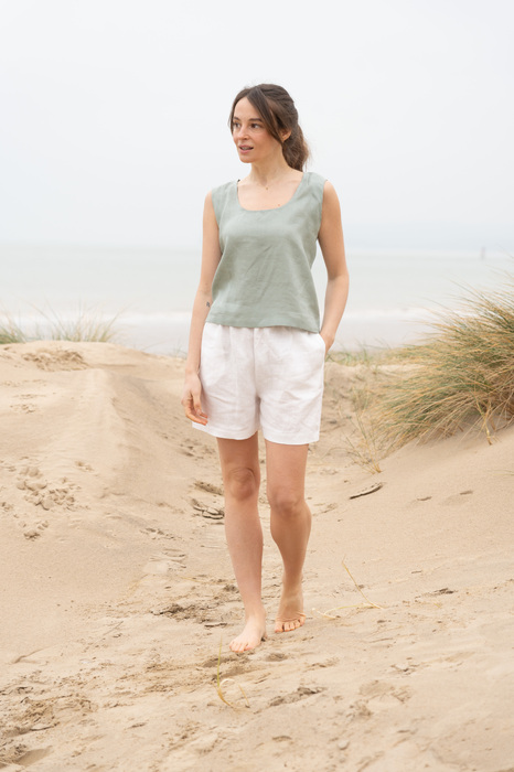 Model on beach in linen shorts and vest
