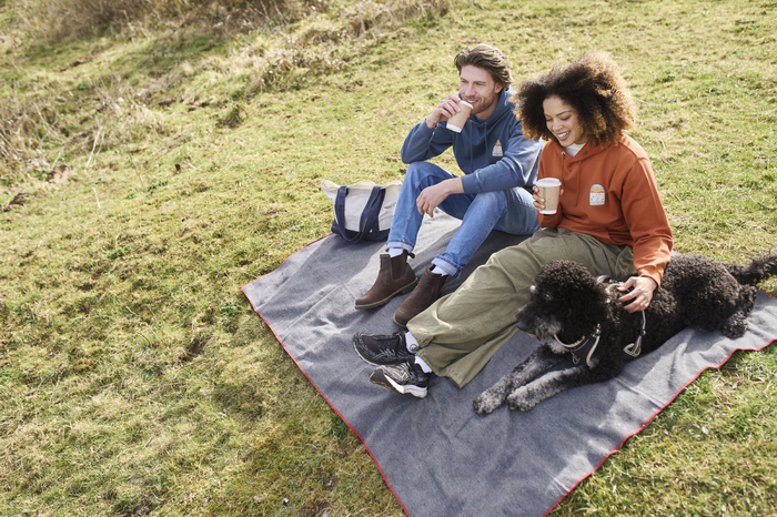 Models sitting on picnic blanket with dog