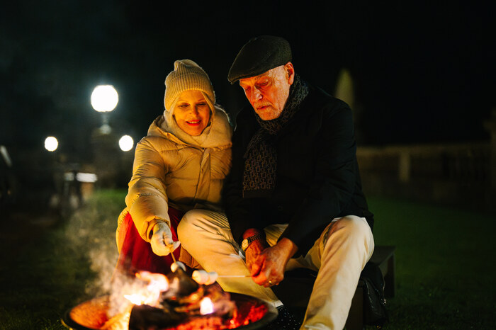 Couple toasting marshmallows over a fire