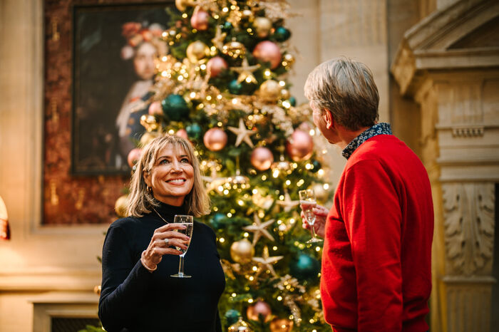 Couple drinking champagne in front of Christmas tree