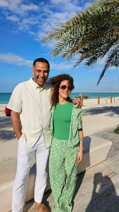 Model couple standing man arm around lady on beach smiling