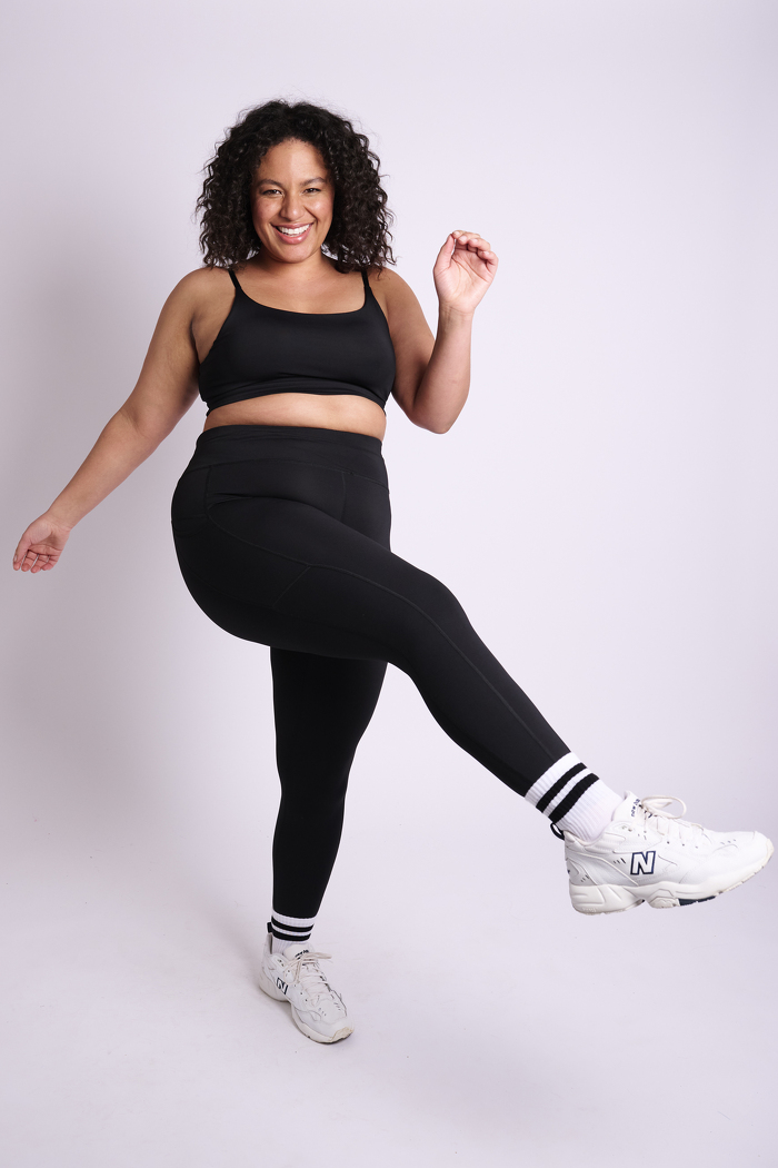 Curve model dressed in fitness wear smiling and kicking leg