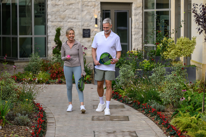 Couple walking together holding tennis racquets