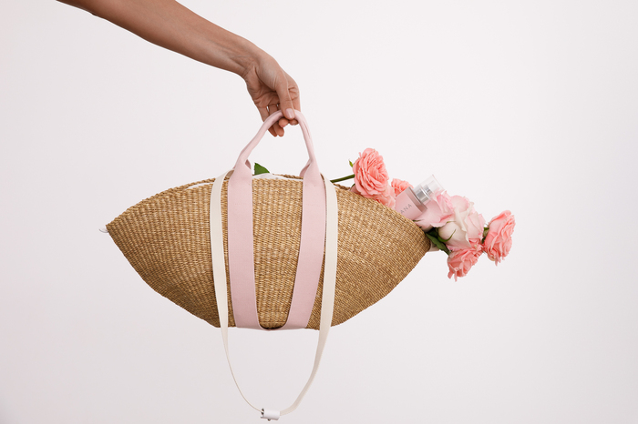 Hand model holding bag with flowers and beauty products