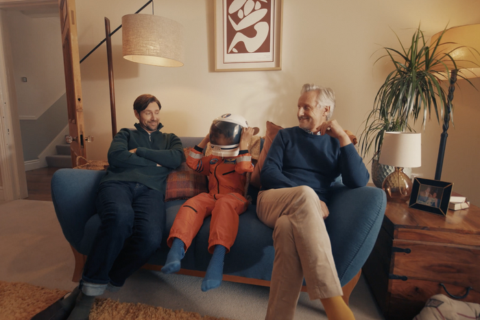 Family on sofa with child dressed in astronaut costume laughing