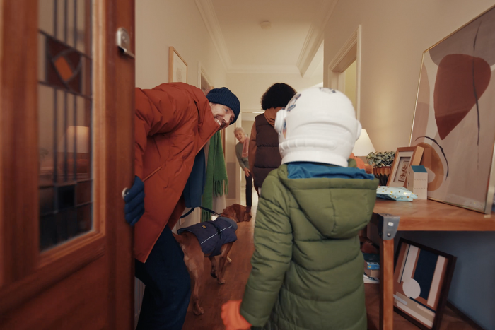 Family coming through front door with dog to visit grandmother