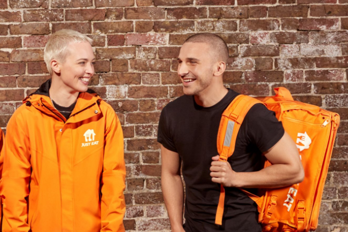 Two models dressed as delivery drivers talking and laughing