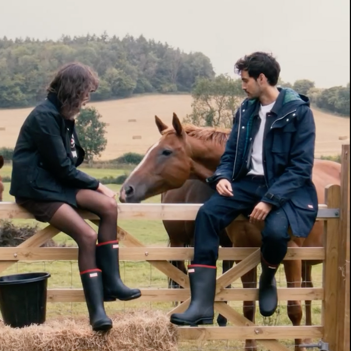 Two models sitting on fence with horse