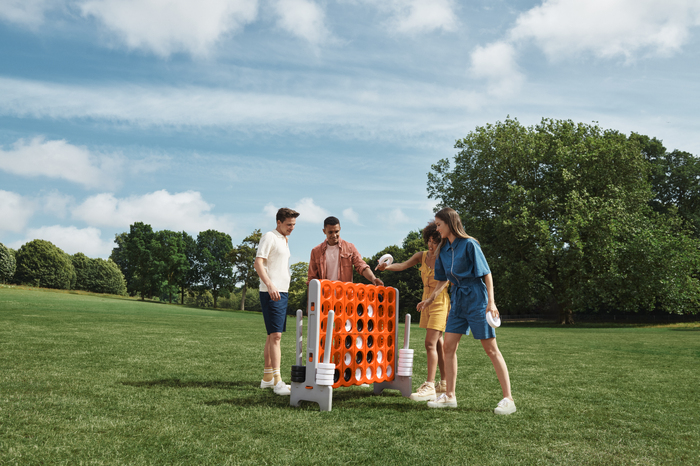 Four models playing games together outdoors on a sunny day