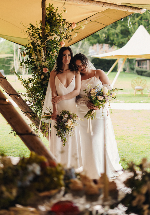 Two brides laughing with flowers