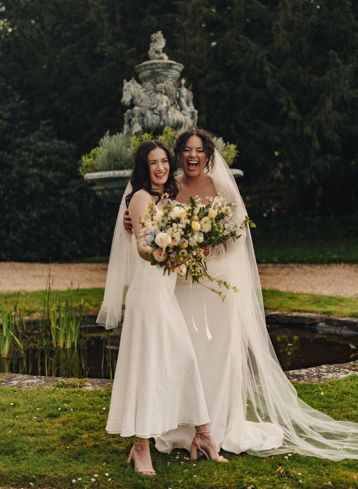 Two brides laughing with flowers